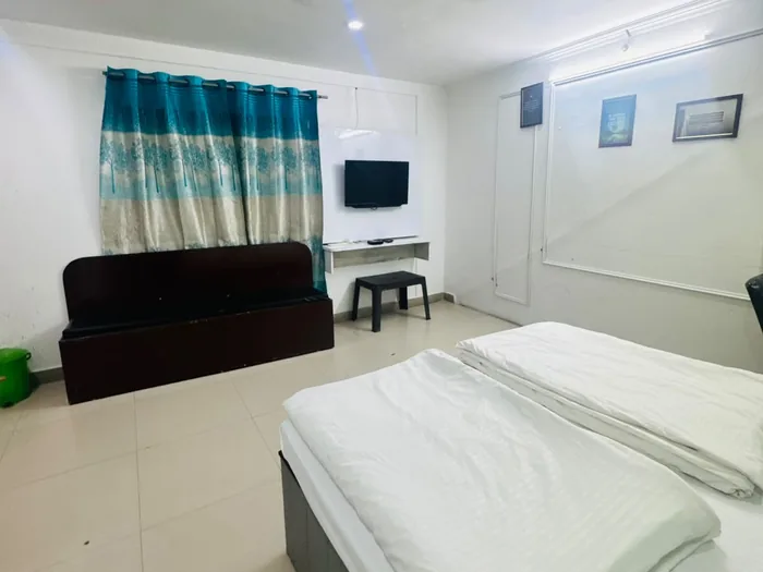 AC room with a TV, a large bed and seating at SS Hotel, Jaunpur